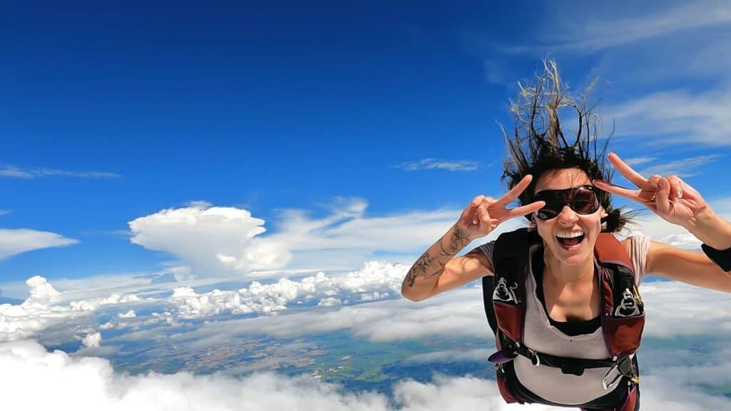 a woman giving the peace sign as she is skydiving.