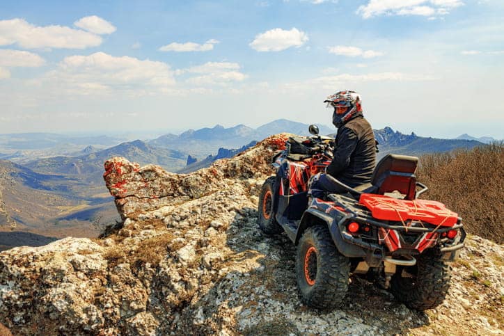An ATV driver is parked on the edge of a cliff.