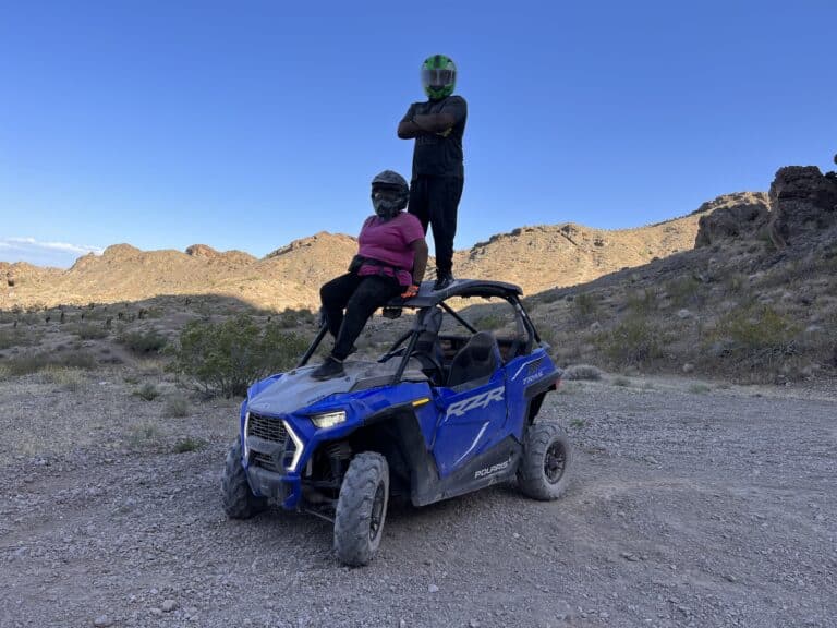 Adventurers on a blue off-road vehicle in Nevadas rocky desert near the Colorado River. Explore Las Vegas ATV tours under clear skies.