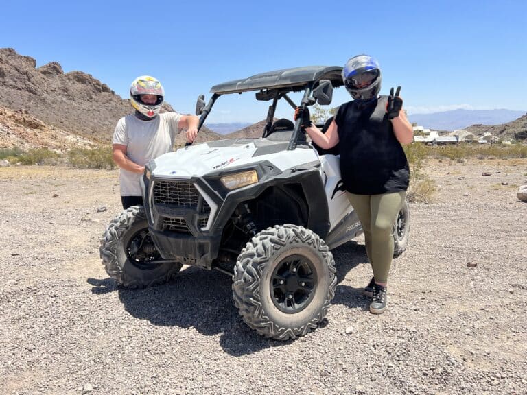 Explore Nevadas rocky terrain on an ATV tour near Las Vegas. Riders in helmets strike poses with mountains and blue skies as their backdrop.