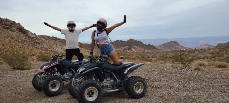 Adventurers in helmets enjoy an ATV tour near Las Vegas, posing amidst Nevadas rocky terrain with the Colorado River beyond.