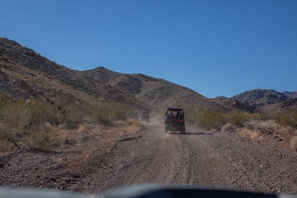 The back of two Awesome Adventure RZRs while on a trail. 