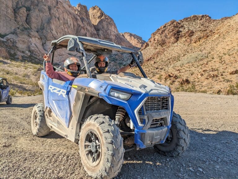 Experience thrilling Las Vegas ATV tours: two adventurers in a blue RZR navigate Nevada cliffs. Perfect day for a Colorado River ride!.