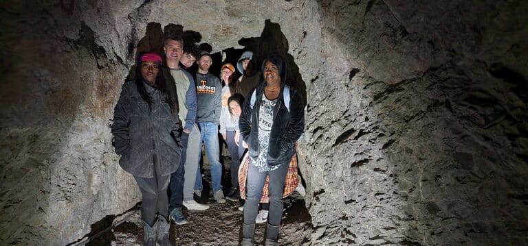 Exploring a dim cave near Las Vegas, visitors in casual attire enjoy the Historic Gold Mine Tour, capturing memories of Nevadas past.
