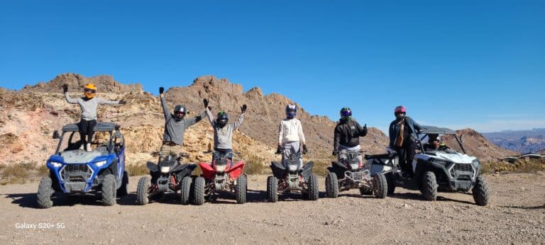 Six thrill-seekers celebrate after an exhilarating Las Vegas ATV Tour in Nevadas desert, near the Colorado River and Ghost Towns.