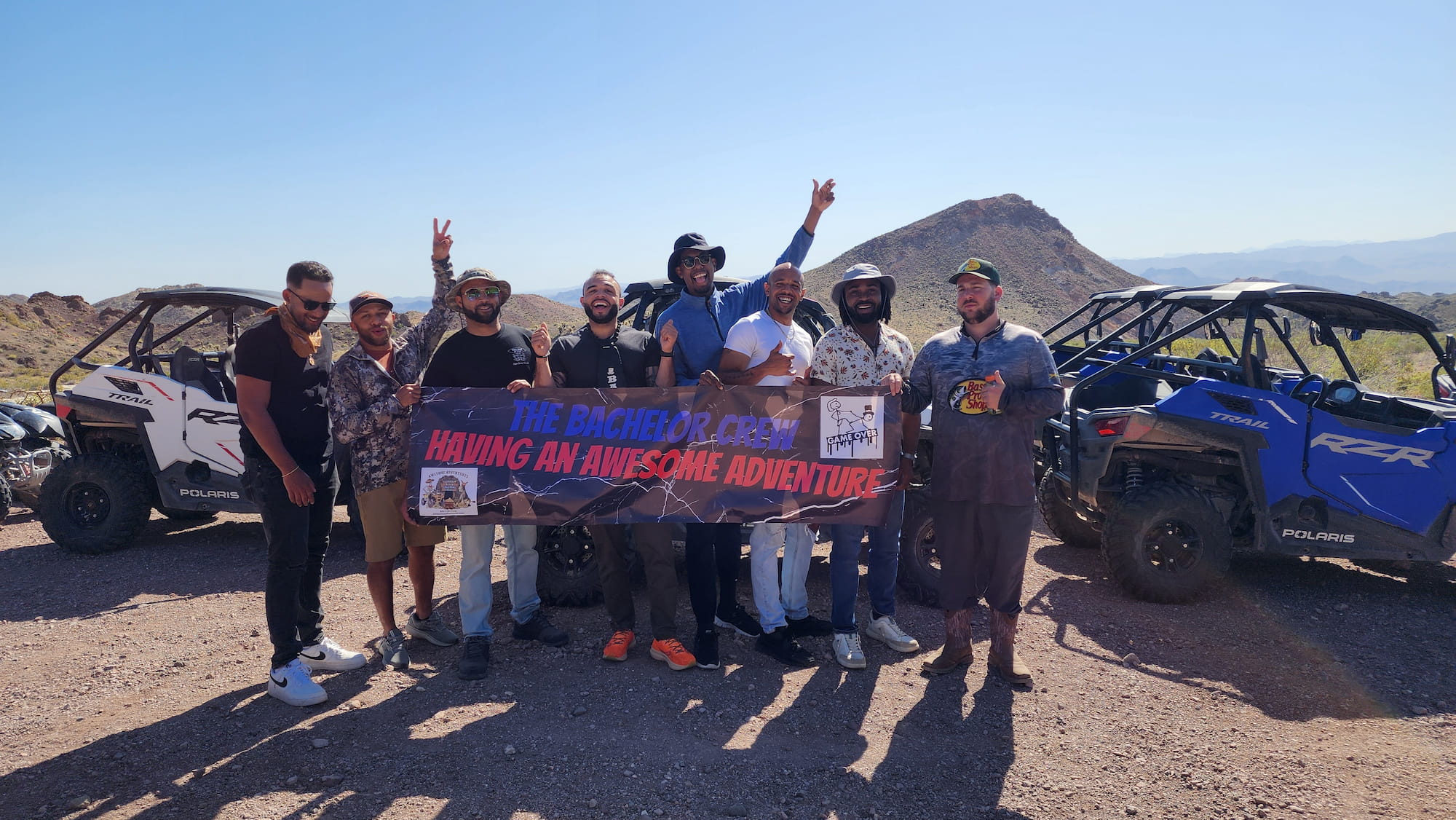 Group off-roading in Nevadas rugged landscape near Colorado River, smiling with peace signs on their Las Vegas RZR adventure tour.