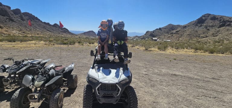 Adventure seekers on an RZR, helmets on, prepare for ATV tours near Las Vegas. A quad bike awaits under Nevadas clear skies for ghost town sightseeing by the Colorado River.