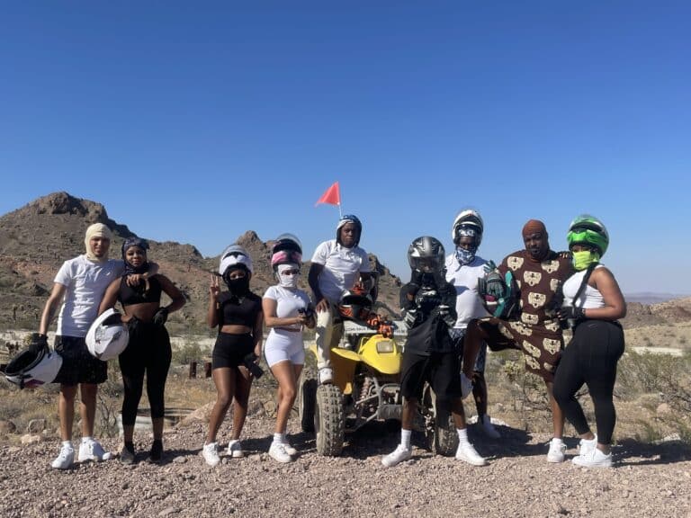 Group of 9 enjoys Las Vegas ATV Tours in Nevada, with helmets & activewear against rocky desert hills near the Colorado River.