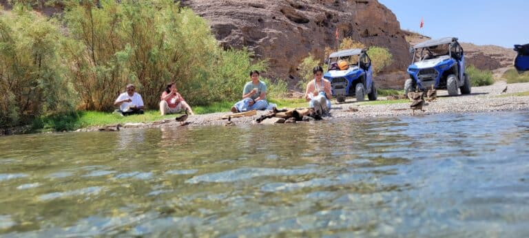 By a serene Colorado Riverbank in Nevada, enjoy Outdoor Adventures with ATV tours and RZR rides near Las Vegas amidst rocky cliffs.