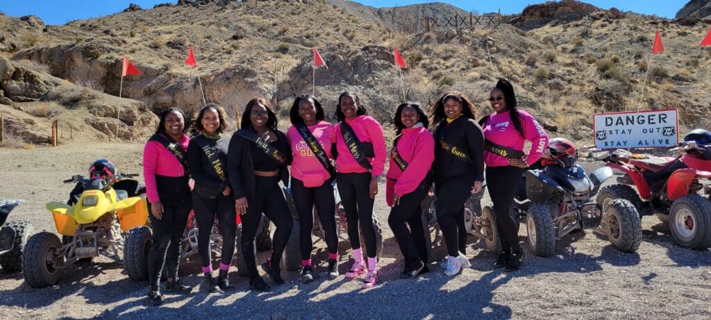 Nine women in pink and black pose by ATVs in Nevadas desert. Enjoy Las Vegas ATV tours with views of the Colorado River!.