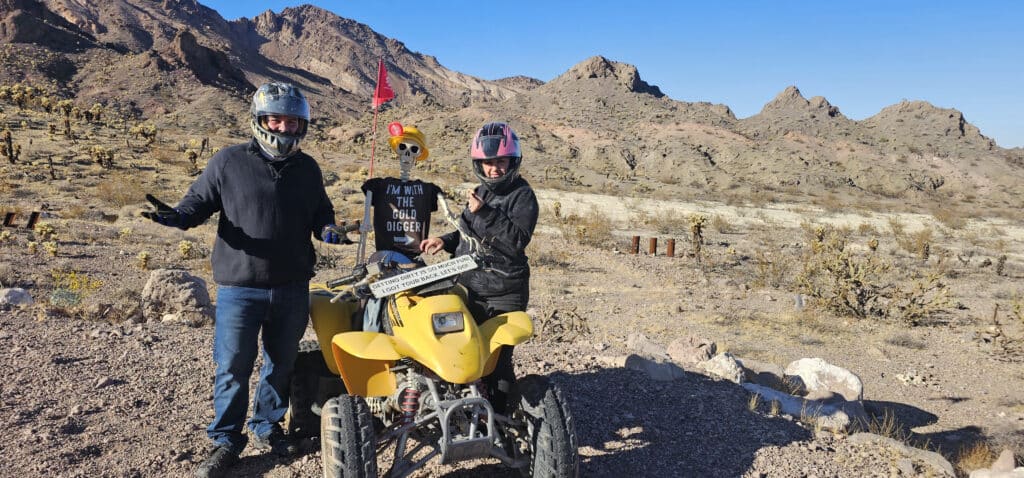 Two adventurers with a skeleton and a yellow ATV in Nevadas desert near Las Vegas, perfect for thrilling RZR off-road rides by the Colorado River!.