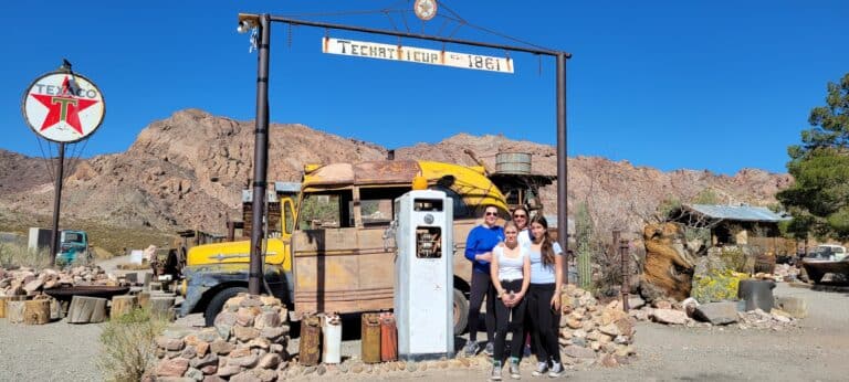 Three visitors at a vintage gas pump in a Nevada desert, near Las Vegas. Discover ATV tours & Ghost Town sightseeing by the Colorado River.