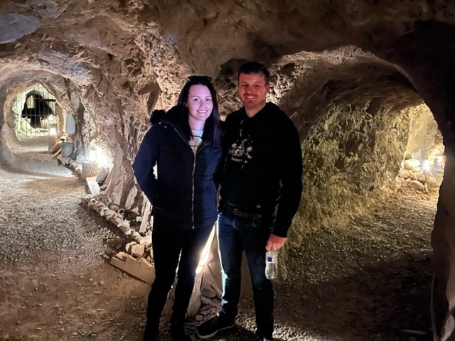 A couple beams in a dim cave at Eldorado Canyon, Nevada, near Las Vegas. Ideal for ATV tours or Ghost Town sightseeing by the Colorado River.