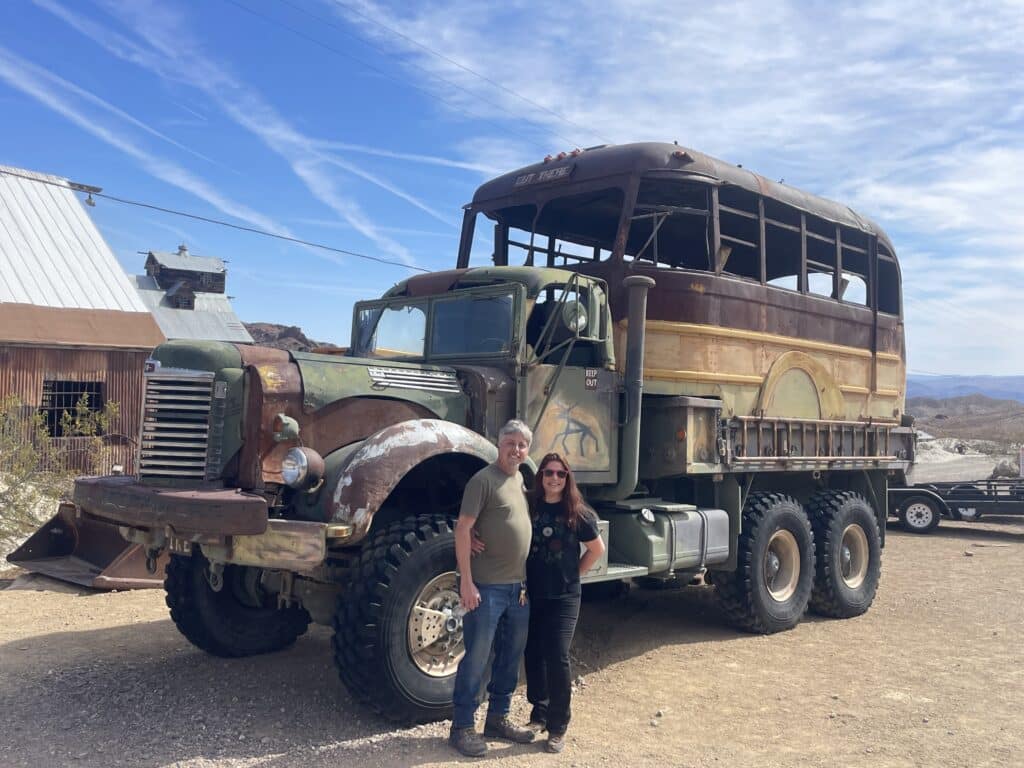 Smiling couple poses by a vintage military truck in a Nevada ghost town—perfect for Las Vegas ATV tours and Colorado River adventures.