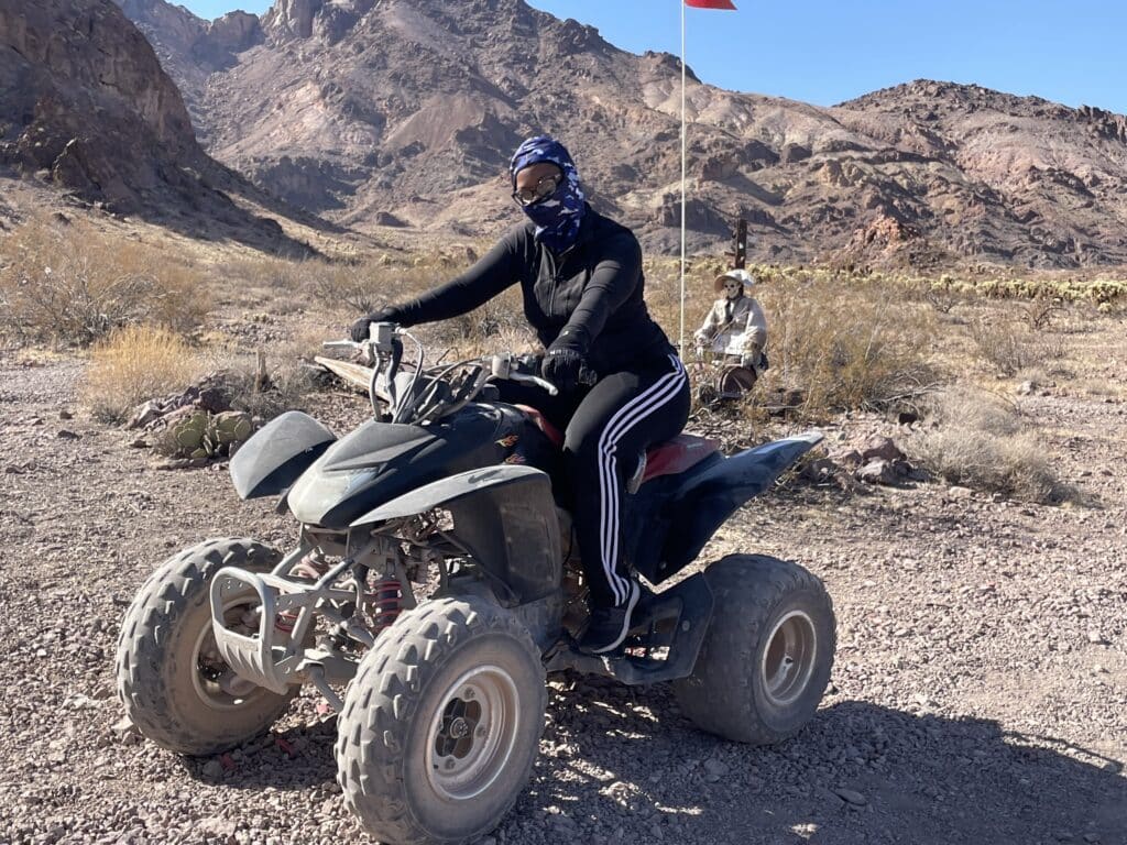 Adventurer in black gear on an ATV with a red flag explores Nevada’s rocky desert near Las Vegas on an epic ATV tour.