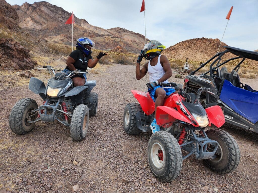 Explore Nevada’s rugged hills near Las Vegas: Two adventurers on ATVs, with an RZR nearby, enjoy off-road tours under a cloudy sky.