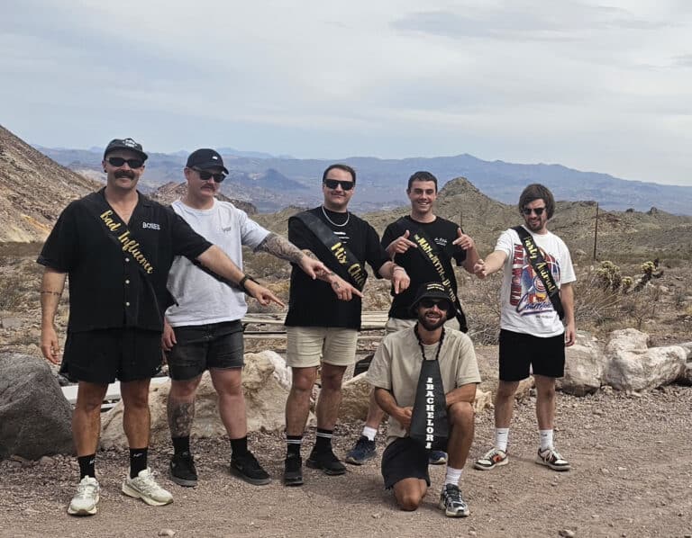 Six friends pose on rocky Nevada terrain near the Colorado River after an exciting Las Vegas RZR off-road ATV tour.