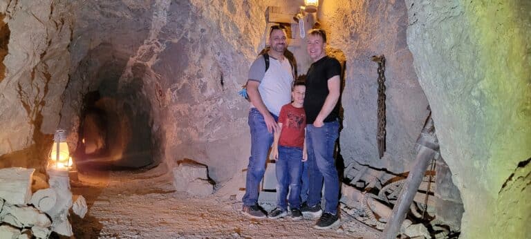 Three friends smile inside a Nevada mine near Las Vegas, surrounded by mining tools—perfect for ATV tours & Ghost Town adventures.