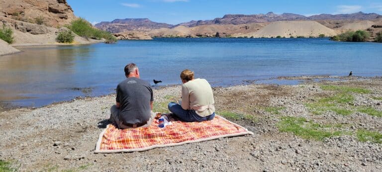 Couple enjoys snacks on a plaid blanket by the Colorado River near Las Vegas, Nevada—perfect for ATV tours or RZR rides.