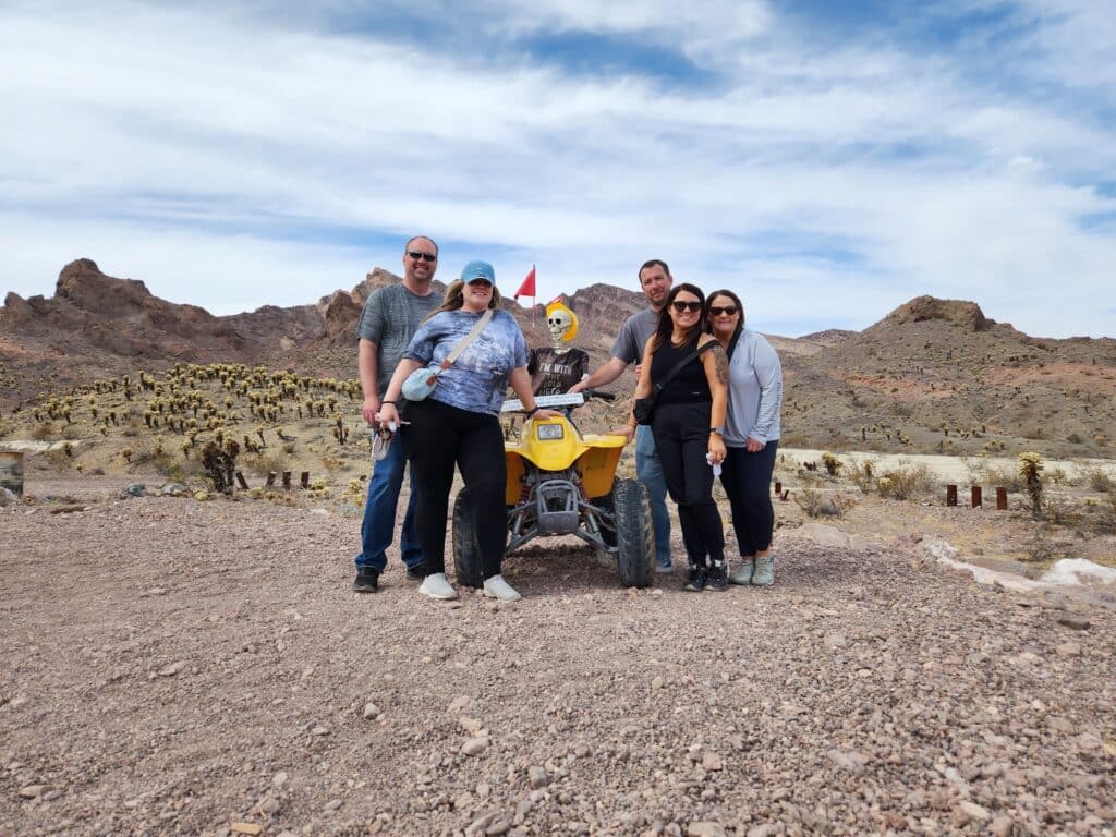 Five friends gather by a yellow ATV in Nevadas rocky desert near Las Vegas for an exciting ATV tour adventure.