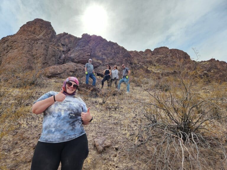 Smiling visitor gives two thumbs up near four friends on a Nevada hillside during an ATV tour near Las Vegas and the Colorado River.