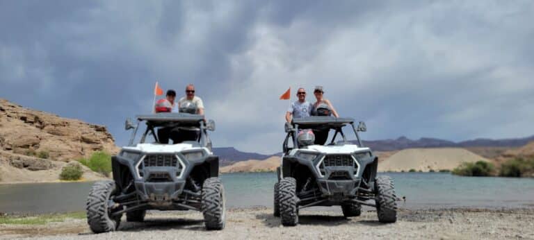 ATV riders gear up for a RZR off-road tour by the Colorado River near Las Vegas, Nevada, with scenic mountains and ghost town views.