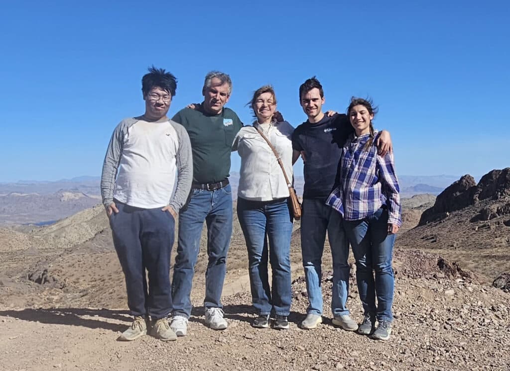 Five friends smile on a rocky Nevada trail near Las Vegas, with desert mountains beyond—perfect for RZR ATV tours & Ghost Town visits.