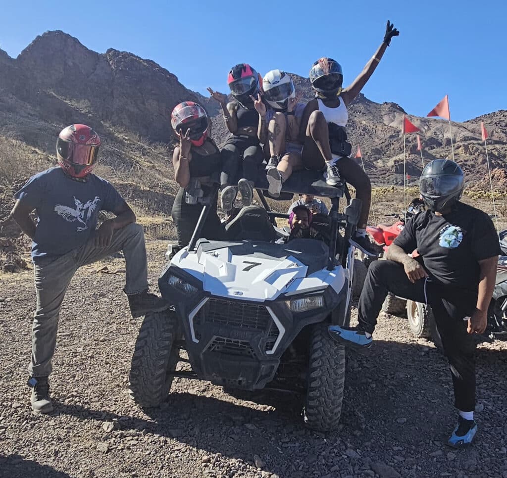 Group in helmets poses with ATV in Nevada desert near Las Vegas, enjoying an exciting off-road RZR tour by the Colorado River.