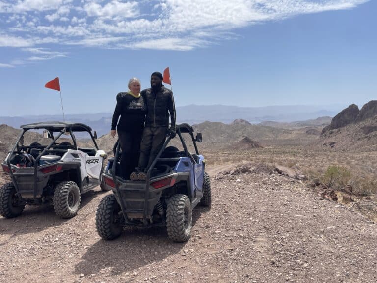 Adventurers stand on a blue ATV near Las Vegas, Nevada, ready for an off-road RZR tour along rocky trails by the Colorado River.