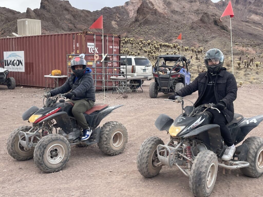 Riders in helmets and jackets sit on ATVs in a Nevada desert near Las Vegas, ready for ATV tours and Ghost Town sightseeing.