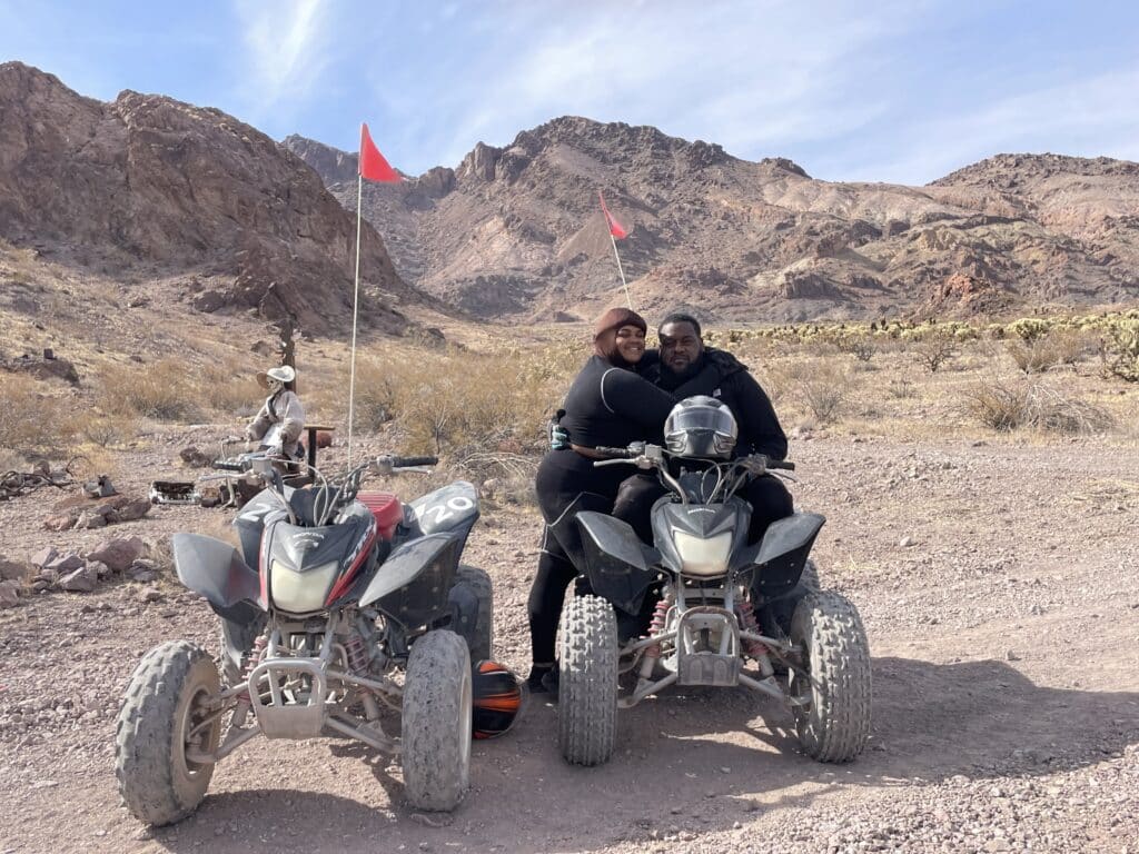 Smiling friends hug on ATVs in a Nevada desert near Las Vegas during a thrilling RZR tour by the Colorado River.