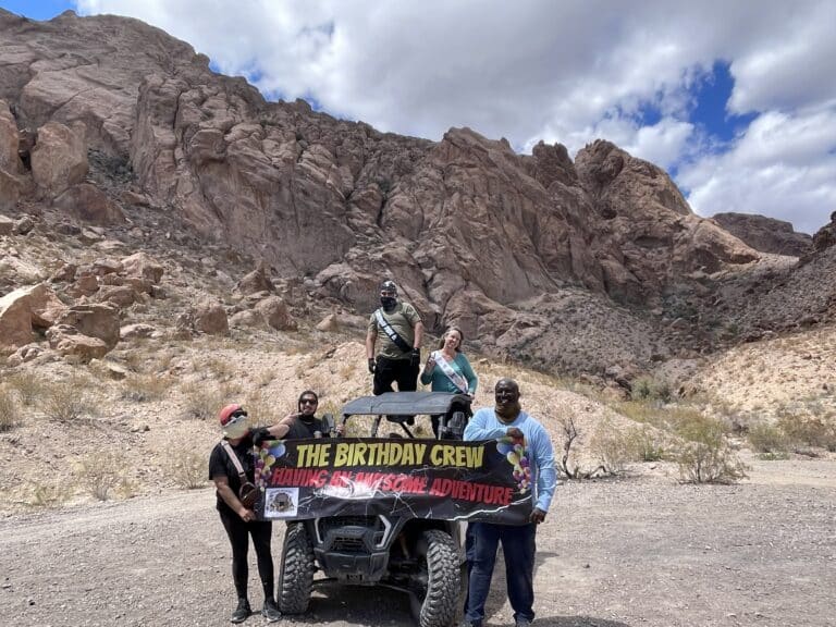 Adventure crew celebrates in Nevada’s desert on an ATV tour near Las Vegas, with mountains and Colorado River views.