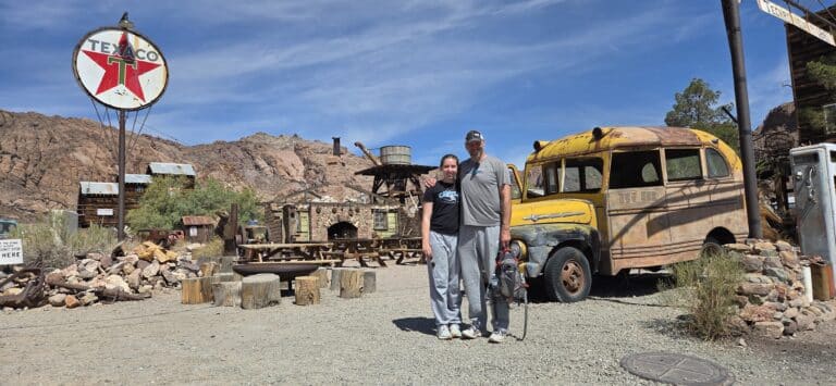 Smiling duo pose arm-in-arm at a vintage Texaco station near Las Vegas’ ghost town—perfect for RZR rides and Colorado River tours.
