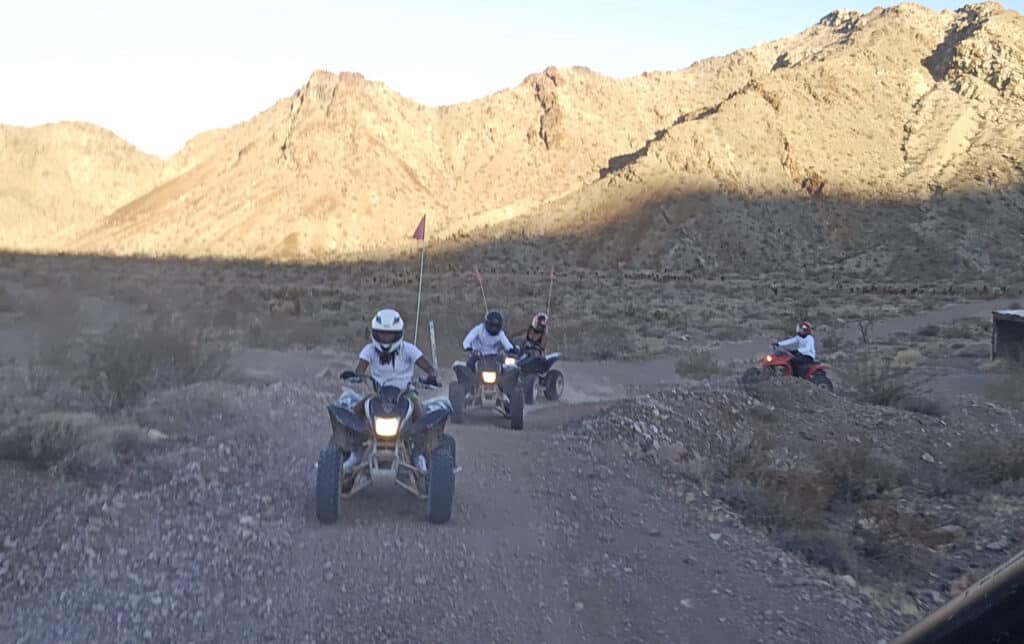 Adventurers enjoy an ATV tour near Las Vegas, riding RZRs along rocky Nevada trails with mountain views under clear desert skies.