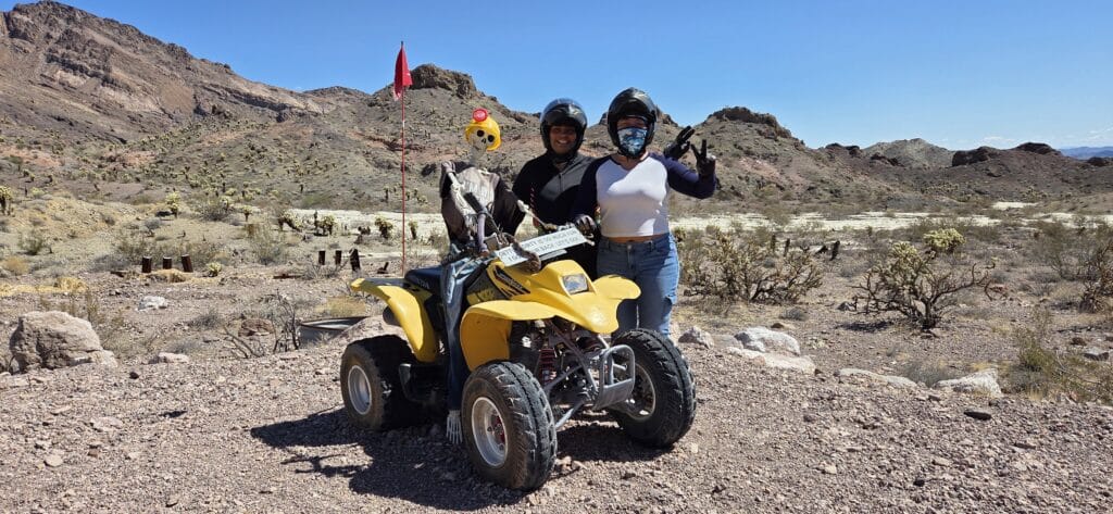 Two people in helmets pose with a yellow ATV near Las Vegas, Nevada—perfect for ATV tours and Colorado River off-road adventures!.