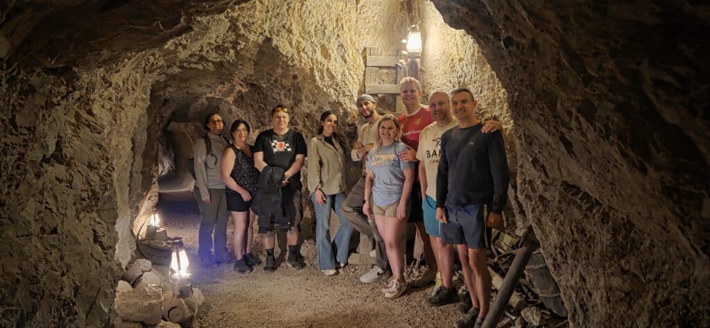 A group enjoys a guided cave tour near the Colorado River in Nevada, smiling under lantern lights after thrilling Las Vegas ATV adventures.