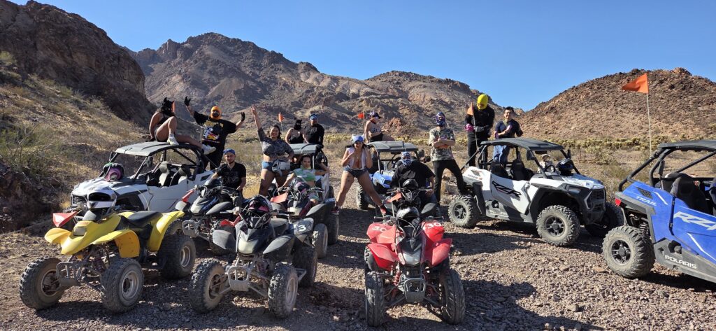 Group enjoying an ATV tour near Las Vegas, Nevada—posing with off-road vehicles on rocky terrain by the Colorado River.