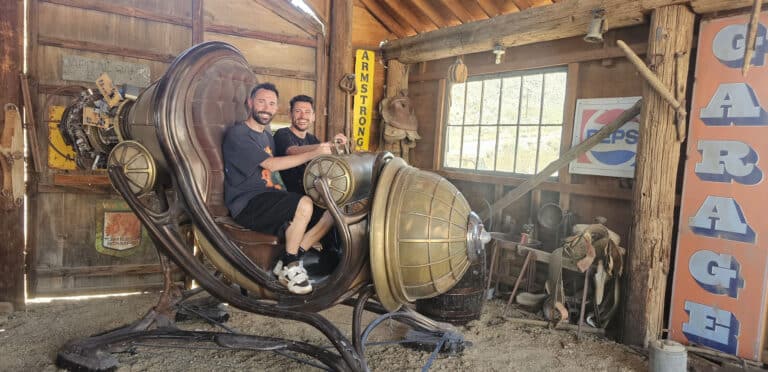 Smiling duo in a steampunk chair at a Nevada ghost town near the Colorado River—perfect stop during Las Vegas ATV and RZR tours!.