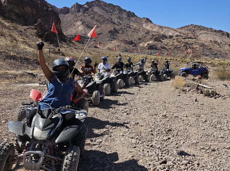 Thrill-seekers enjoy a Nevada ATV tour near the Colorado River; ride RZRs by Las Vegas with red flags and desert mountain views.