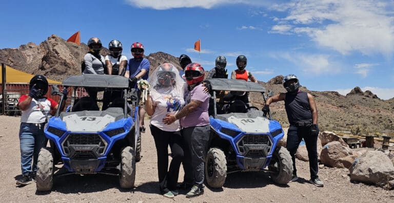 Group in helmets poses with blue RZRs on a Nevada desert ATV tour near Las Vegas and the Colorado River Ghost Towns.