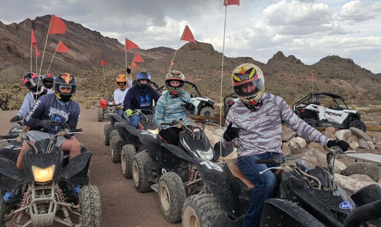 Riders gear up on ATVs with red flags for a thrilling Nevada desert off-road tour near Las Vegas and the Colorado River.