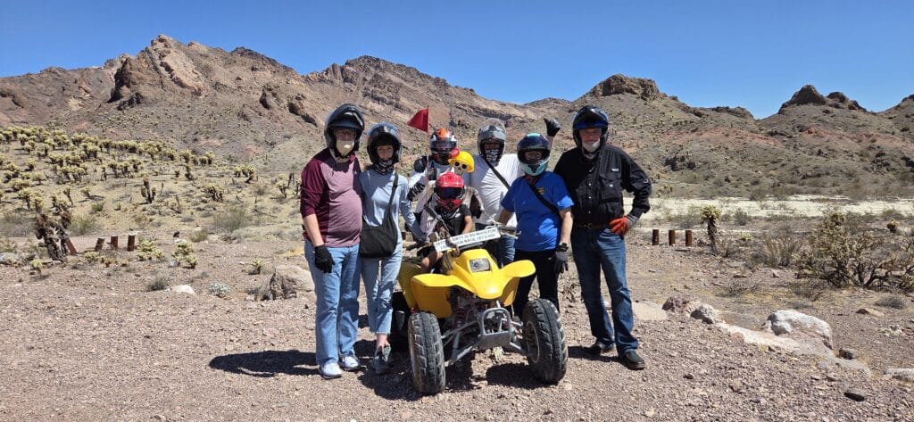 Group in helmets enjoys an ATV tour near Las Vegas, Nevada, with rocky mountains and the Colorado River in the background.