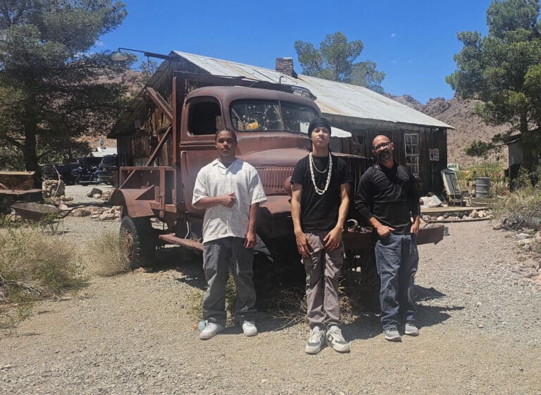 Three men pose by a rusty truck near a Nevada ghost town, perfect for Las Vegas ATV tours and Colorado River off-road adventures.