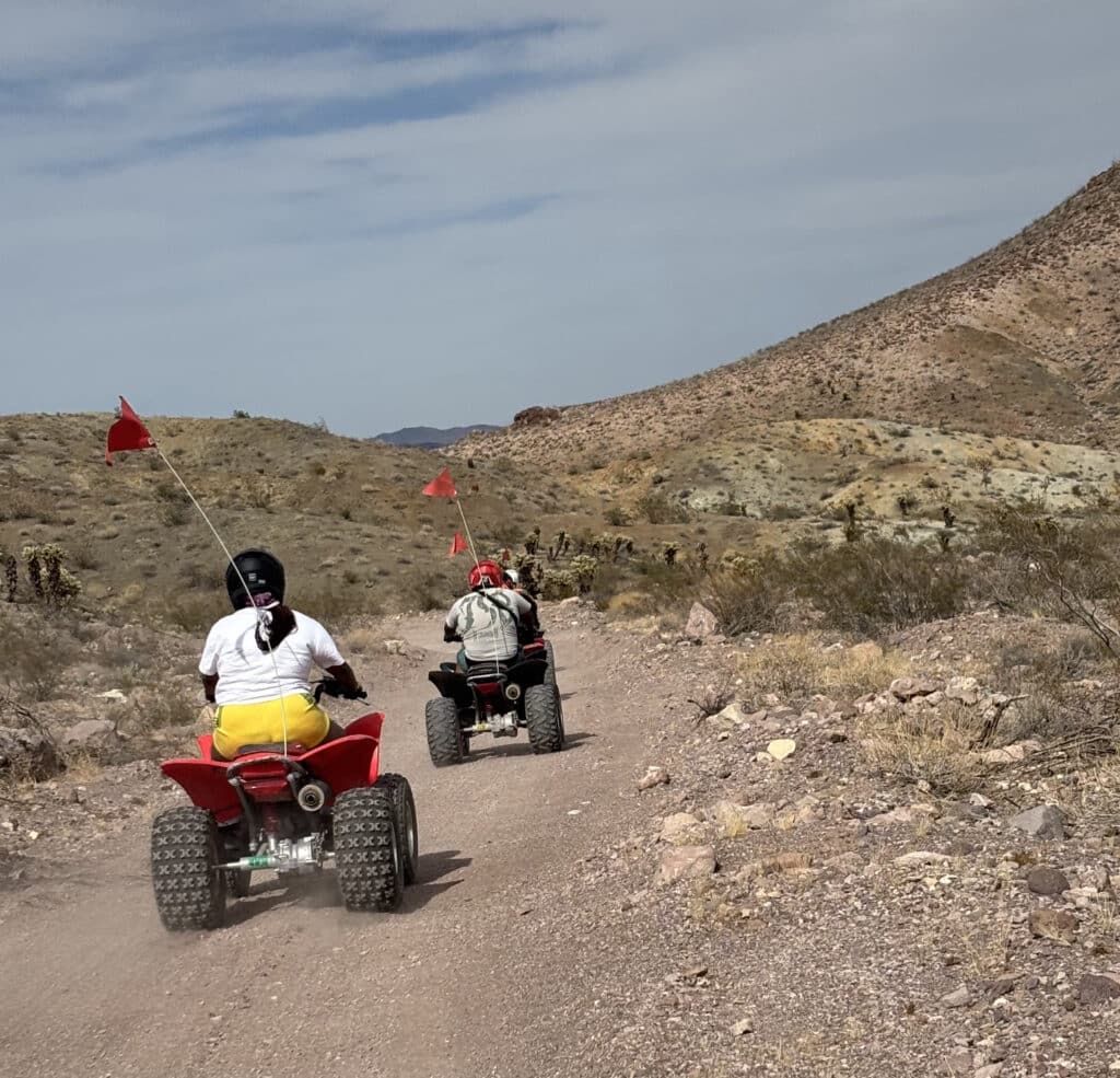 Explore a Nevada desert trail on an ATV tour near Las Vegas with red flags, rocky hills, and stunning Colorado River views.