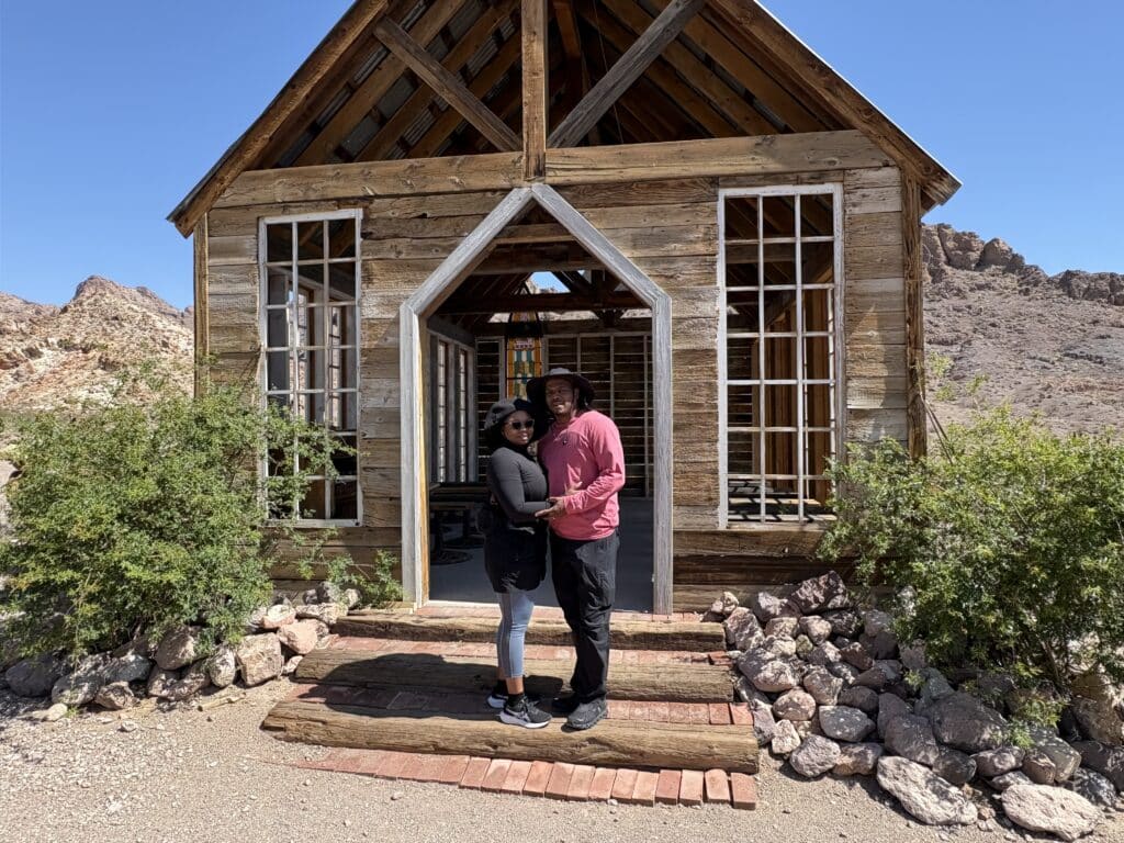 A couple stands on chapel steps in a Nevada ghost town near the Colorado River, perfect for Las Vegas ATV tours and sightseeing.