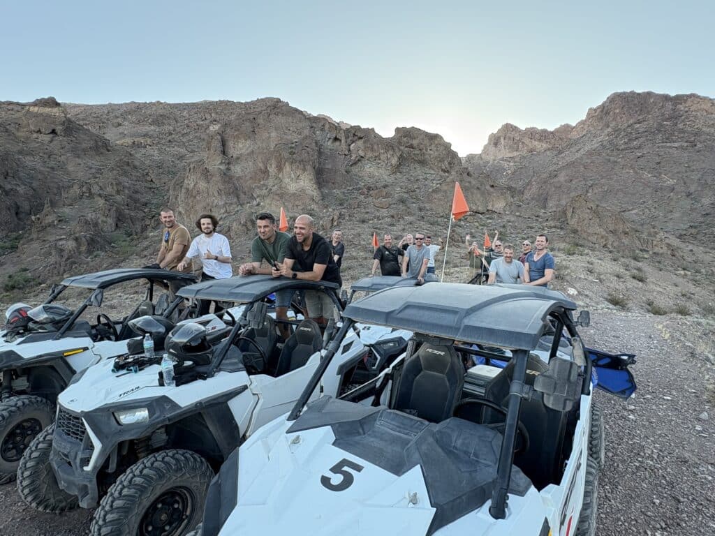 Adventurers enjoy a Nevada desert ATV tour near Las Vegas, parked on a rugged trail with RZRs by the Colorado River.