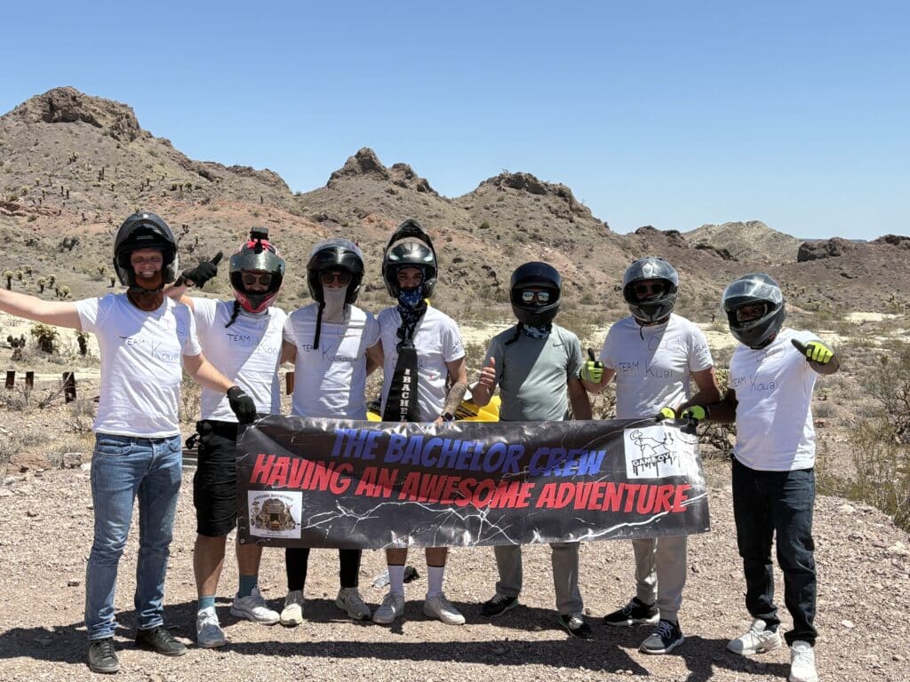 Six friends in helmets pose in Nevada desert near Las Vegas after a thrilling RZR off-road ride by the Colorado River.