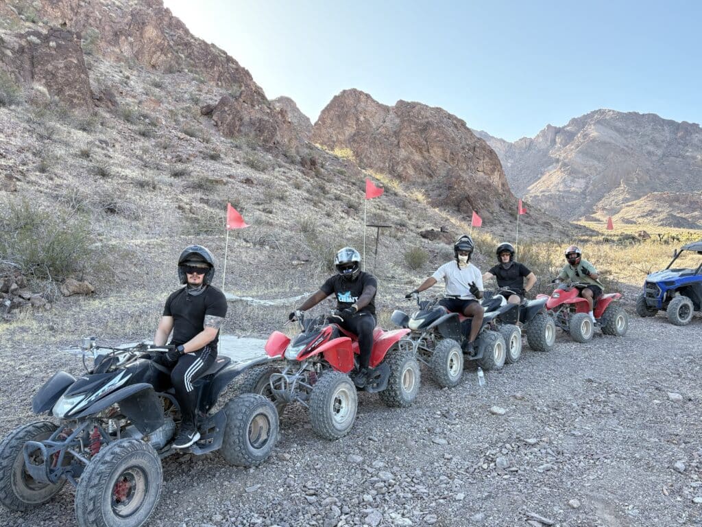 Adventurers in helmets line up on ATVs for a thrilling Las Vegas desert tour near the Colorado River and Nevada ghost towns.