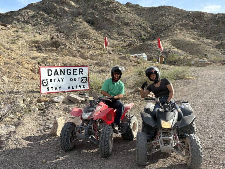 Riders in helmets sit on ATVs by a Danger sign near Las Vegas, Nevada—perfect for Colorado River ATV tours and Ghost Town rides.