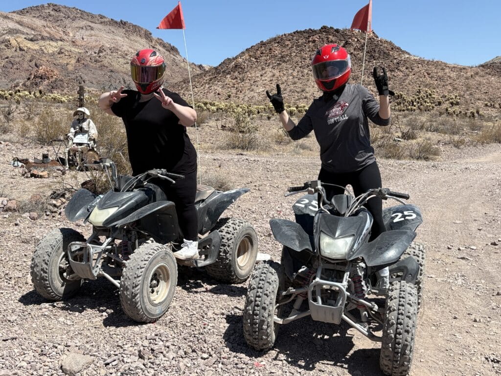 Two riders in red helmets pose on ATVs in the Nevada desert near Las Vegas, ready for an epic ATV tour by the Colorado River.